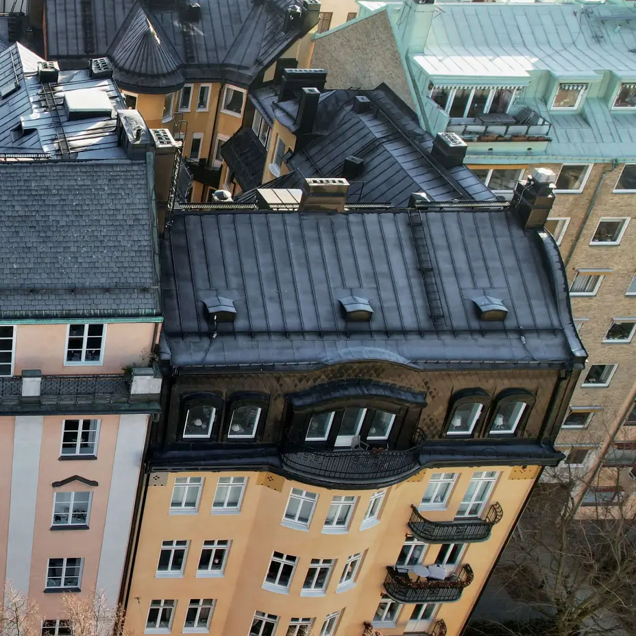 Flerbostadshus med svart plåttak och renoverad fasad där Kinnunens Plåtslageri AB utför både plåtslageriarbeten och fasadrenovering