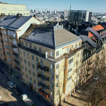 Flerbostadshus i stadsmiljö med nytt skiffertak och plåtdetaljer installerade av Kinnunens Plåtslageri AB
