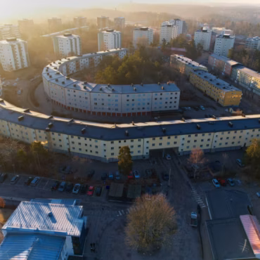 Flygfoto över flerbostadshus med nytt bandtäckt plåttak, tilläggsisolerade fasader och nya fönsterbleck utfört av Kinnunens Plåtslageri AB